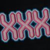 Beaded geometric cross-stitch pattern with pink, blue, and black colours on black fabric.