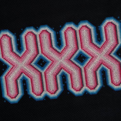 Beaded geometric cross-stitch pattern with pink, blue, and black colours on black fabric.